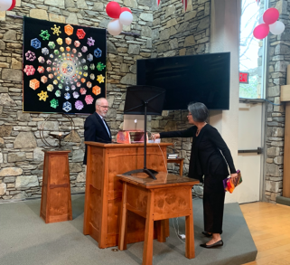 two people at church pulpit with computer set up to record