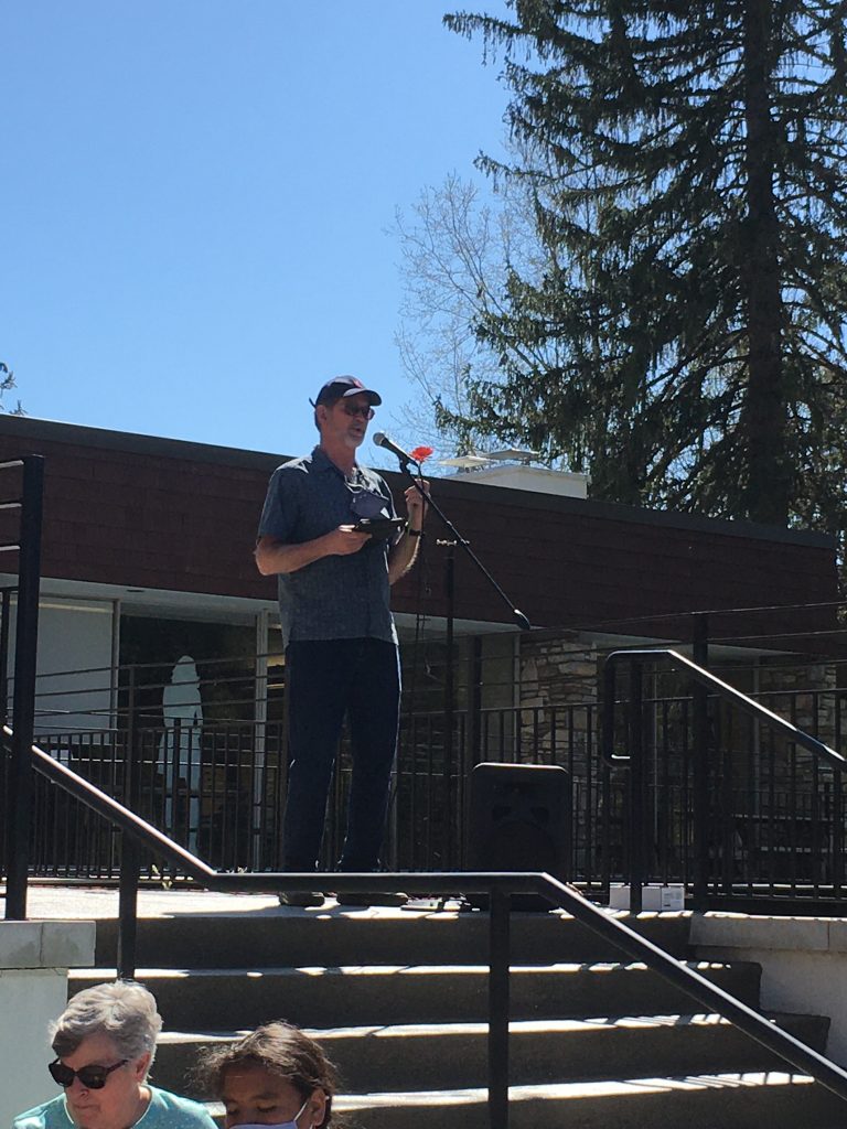 Minister casually dressed speaking at microphone outside church