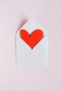 red heart peeking out of white envelope